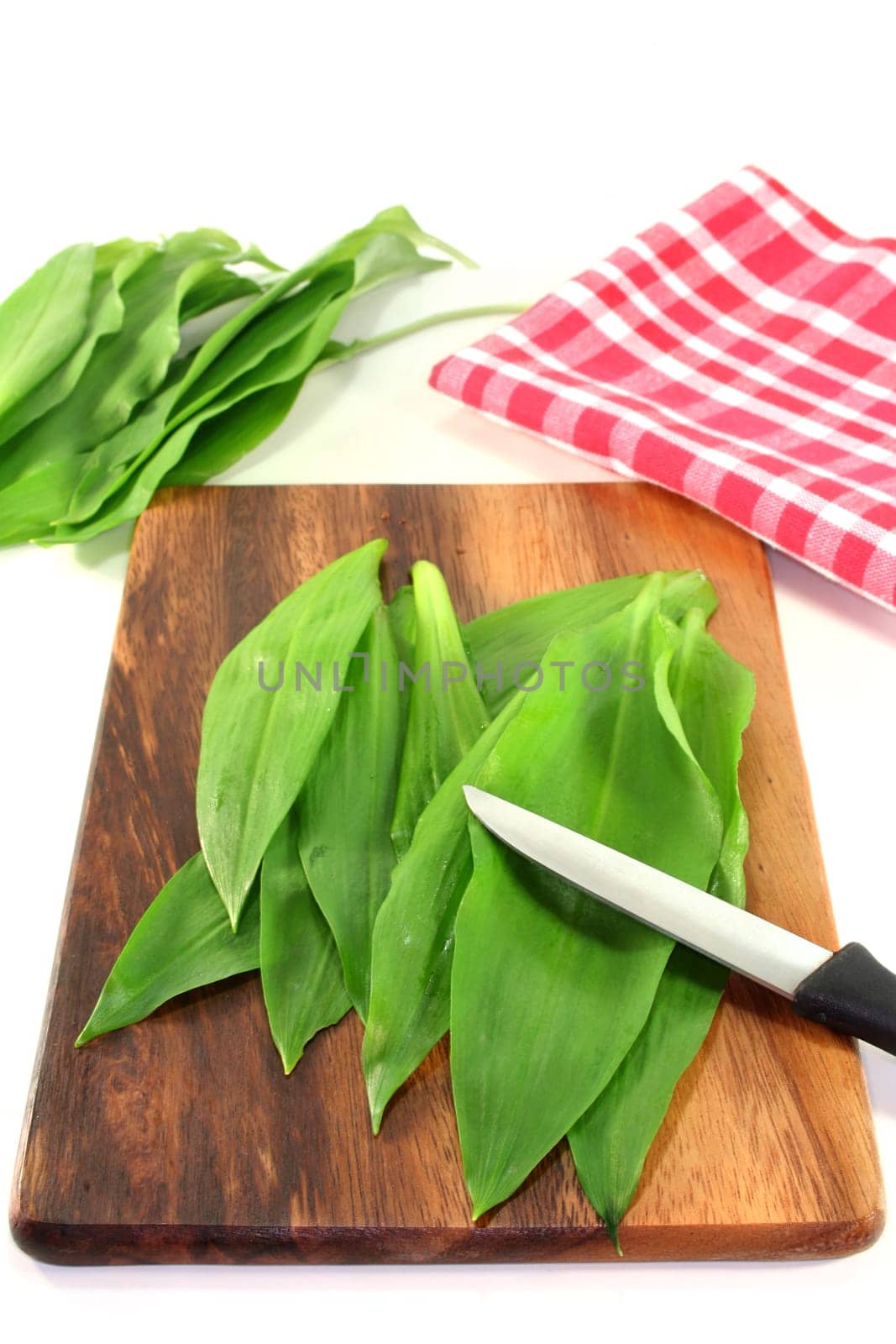 fresh wild garlic and a knife on a wooden board