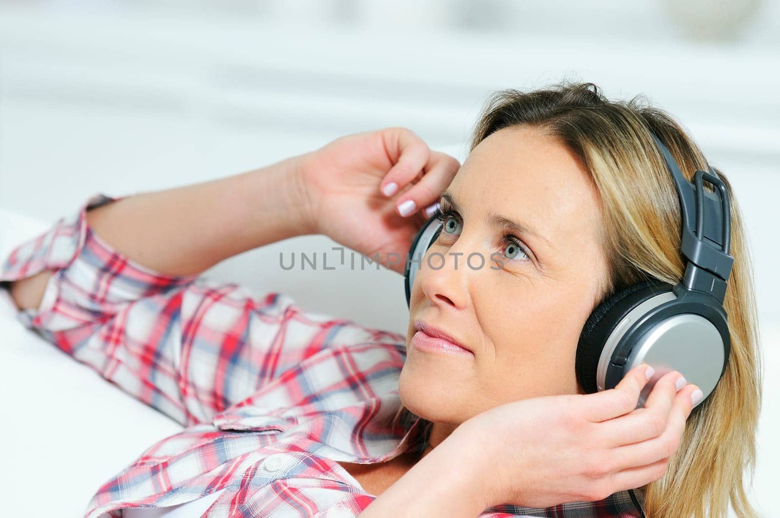 blond woman relaxing at home, listening music with a headphone