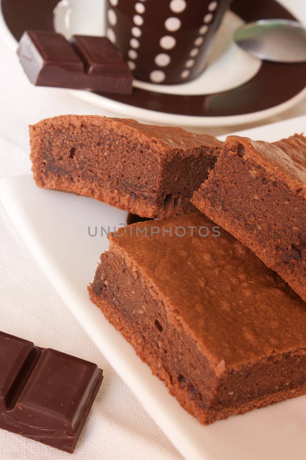 Pieces of chocolate cake on a plate with a cup of coffee in background