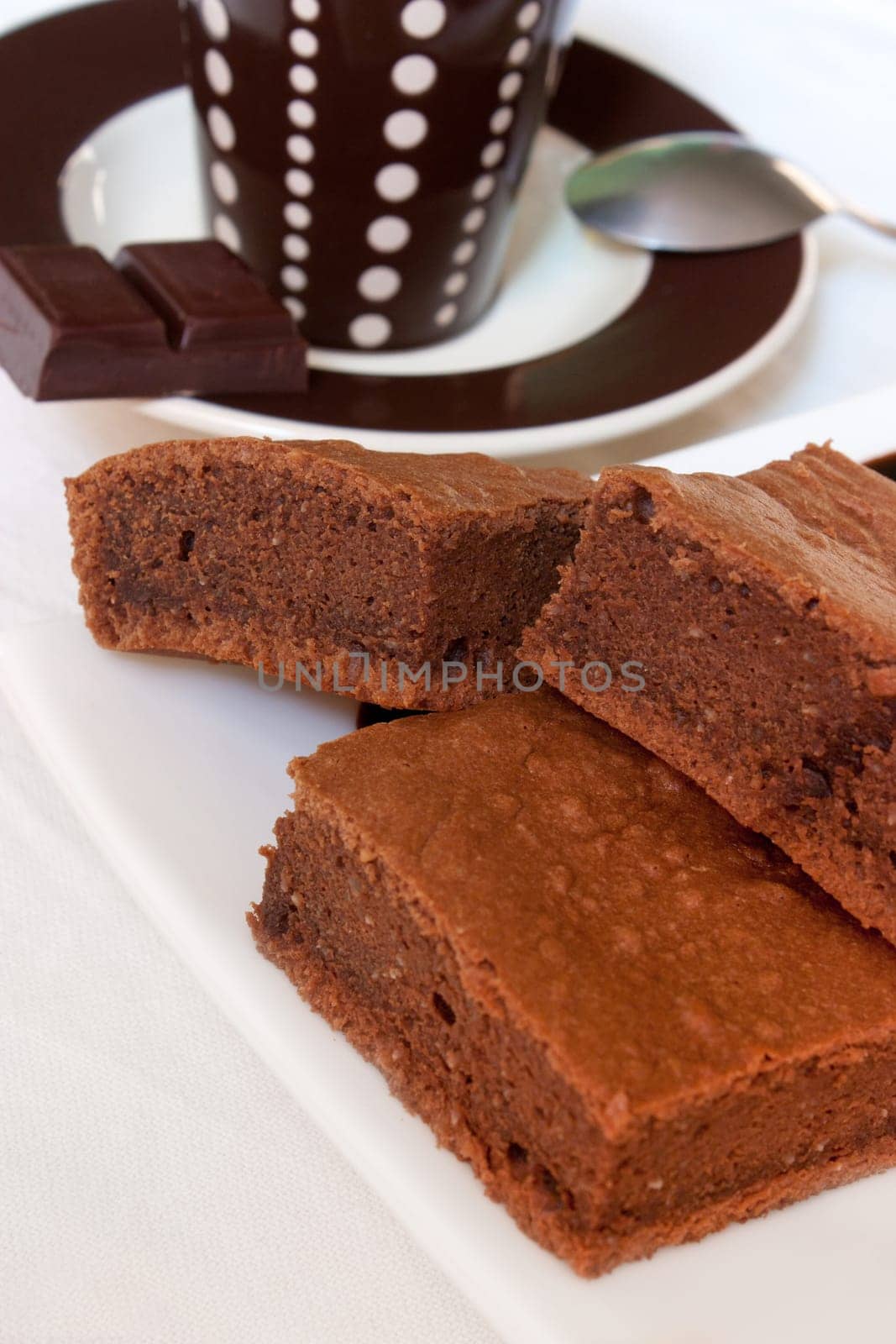 Pieces of chocolate cake on a plate with a cup of coffee in background