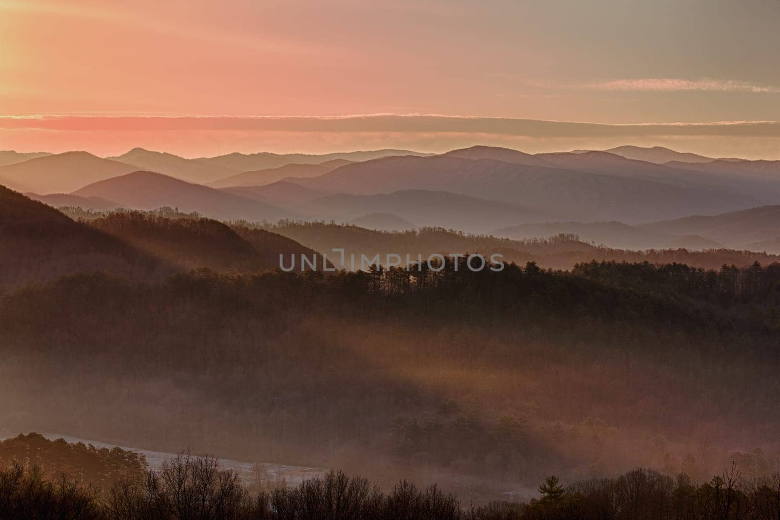 Sun rising over snowy mountains of Smokies in early spring with fog in valleys