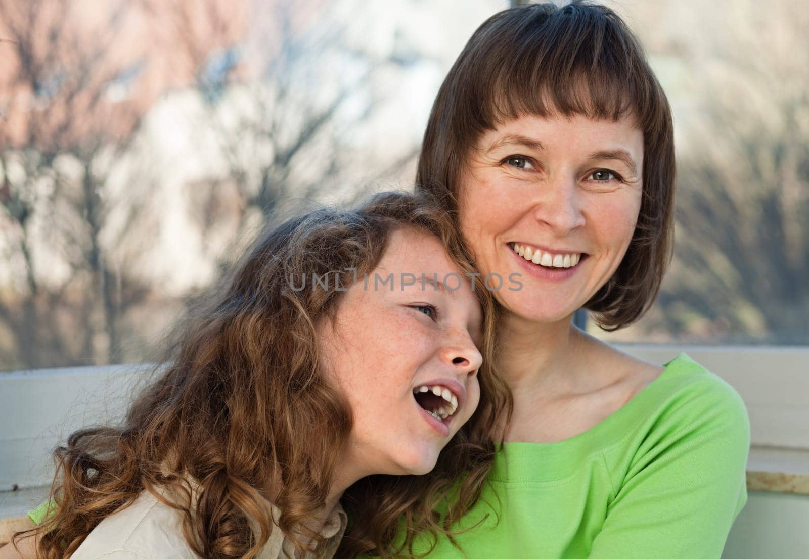 Happy smiling mother together with her teenager daughter at home