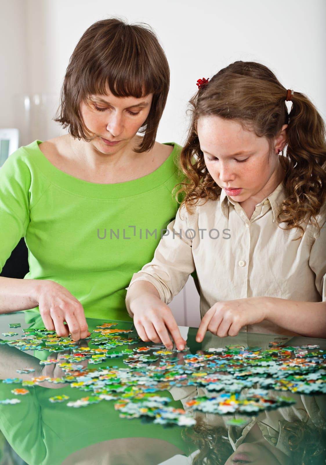 Teenager girl and her mother doing a puzzle at home