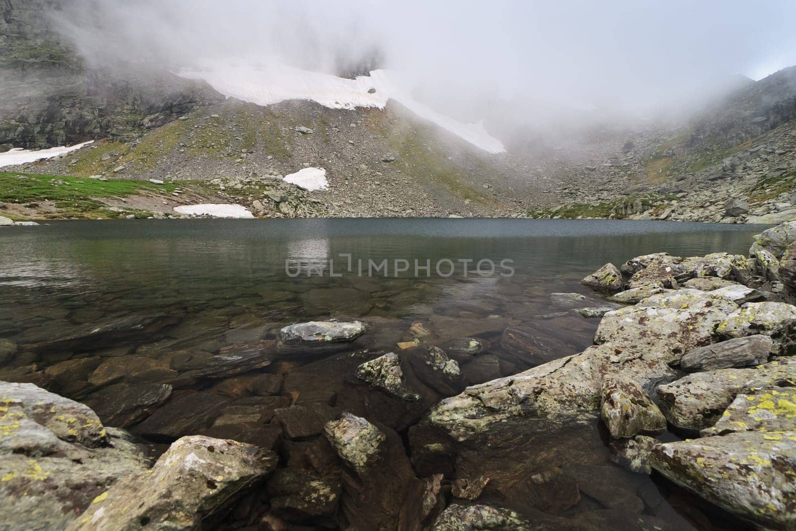 snow and fog near a mountain lake