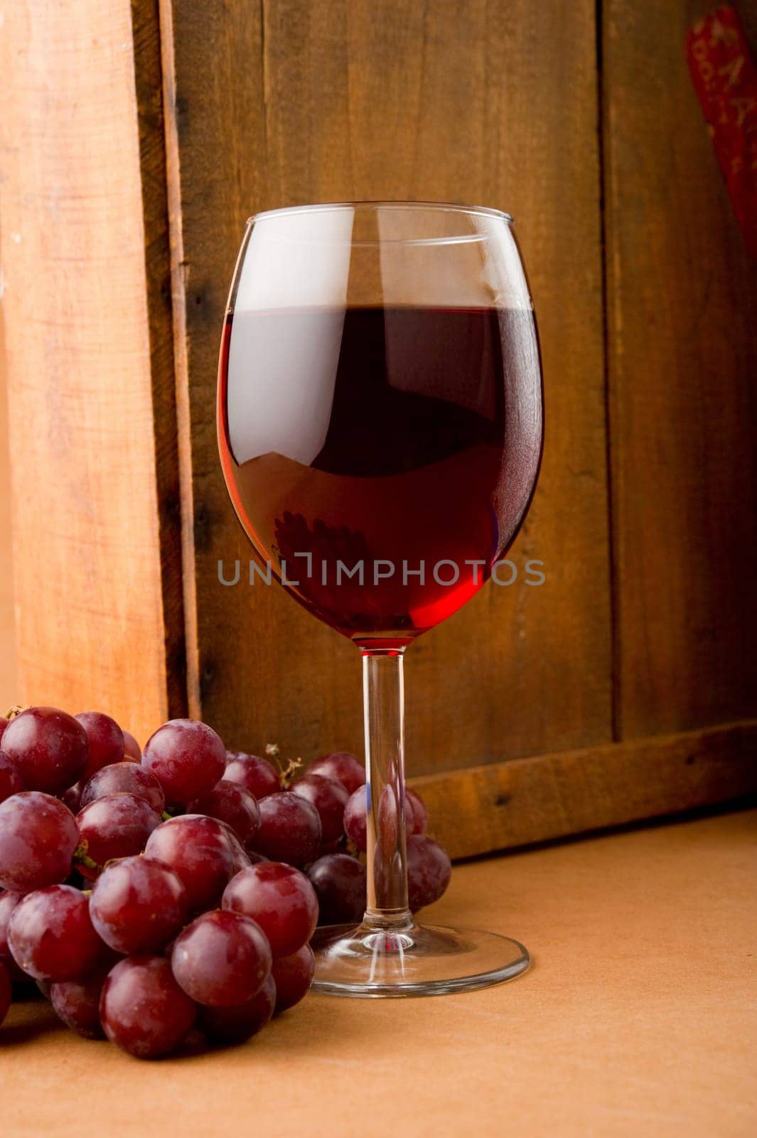 Image of a glass of wine and grapes next to old wooden box
