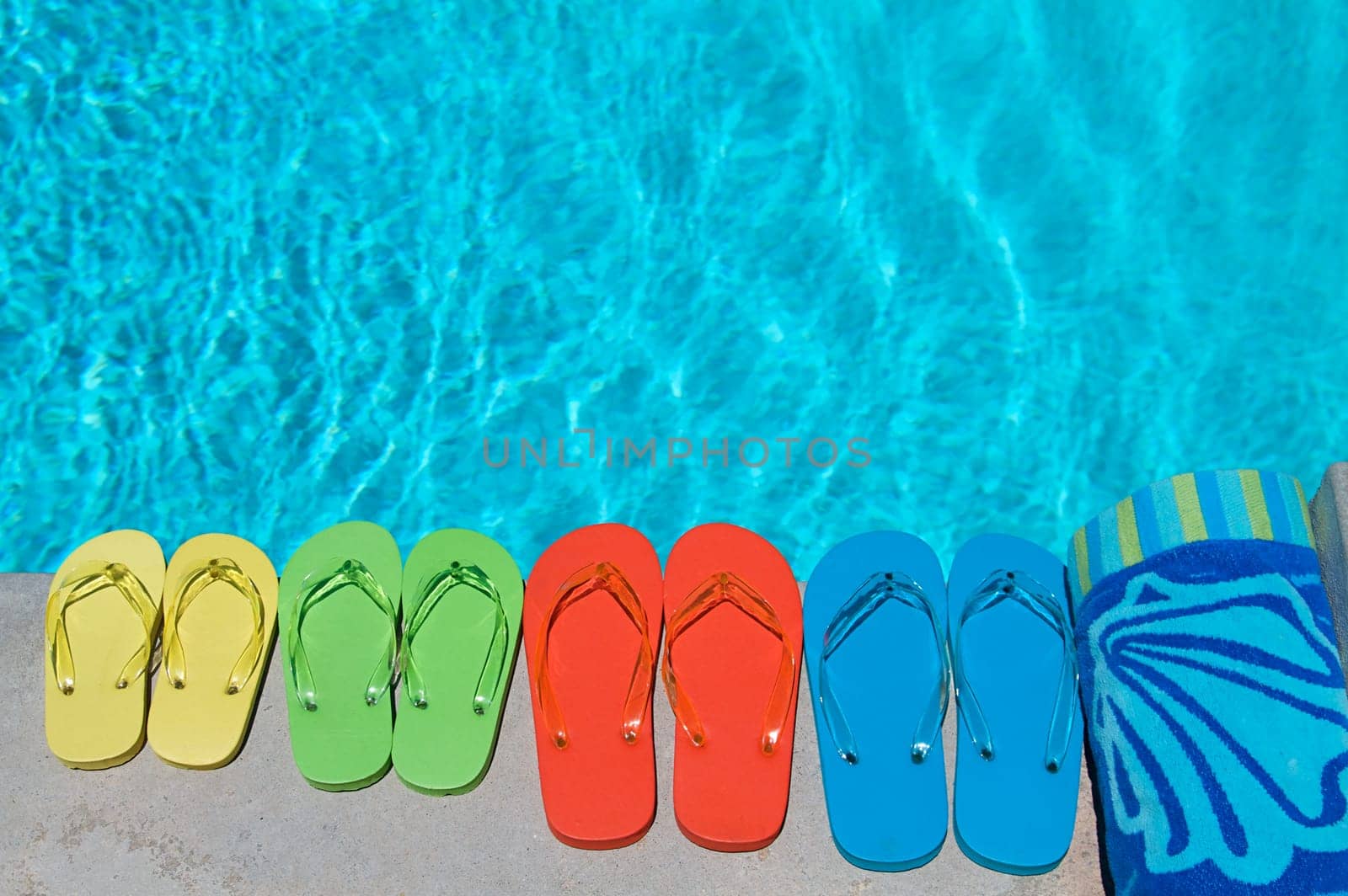 Colored flipflops of a family of four by the swimming pool