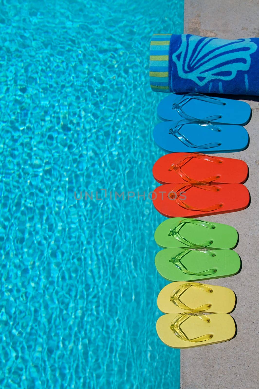 Colored flipflops of a family of four by the swimming pool