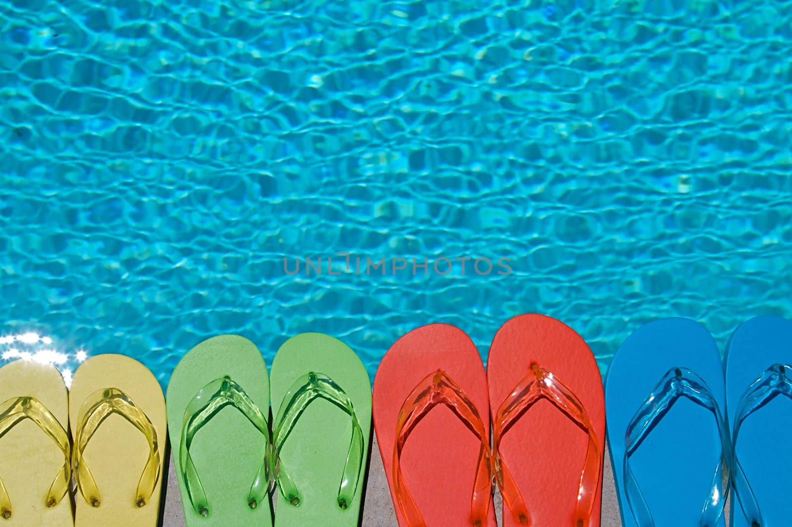 Colored flipflops of a family of four by the swimming pool