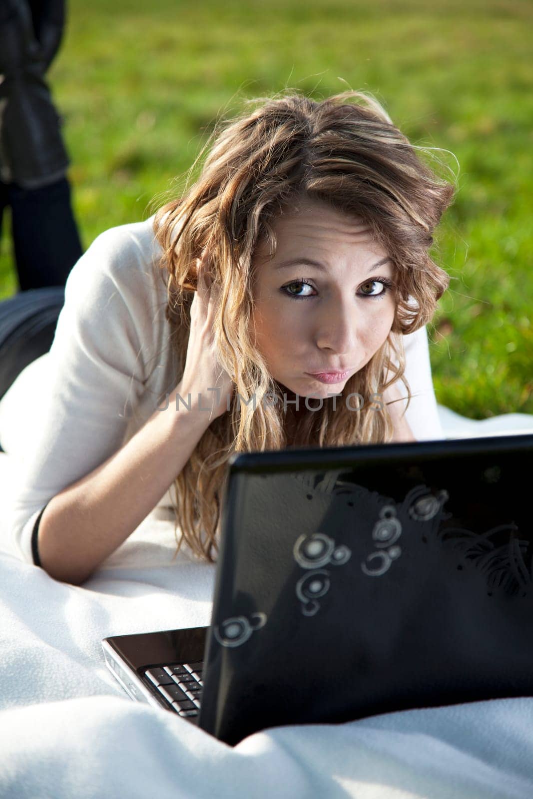 Confused young woman in park with laptop