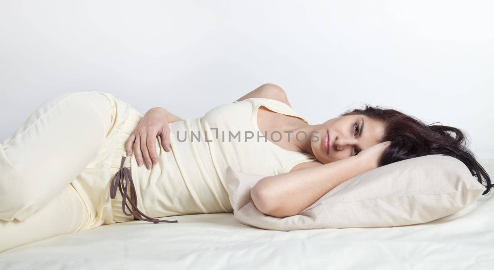 Pretty young brunette woman lying in bed
