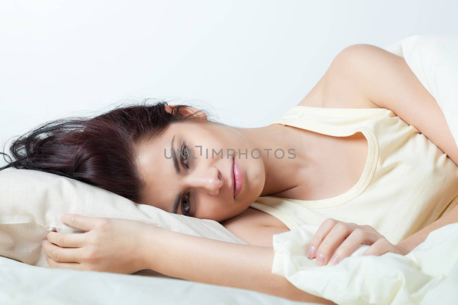 Pretty young brunette woman lying in bed