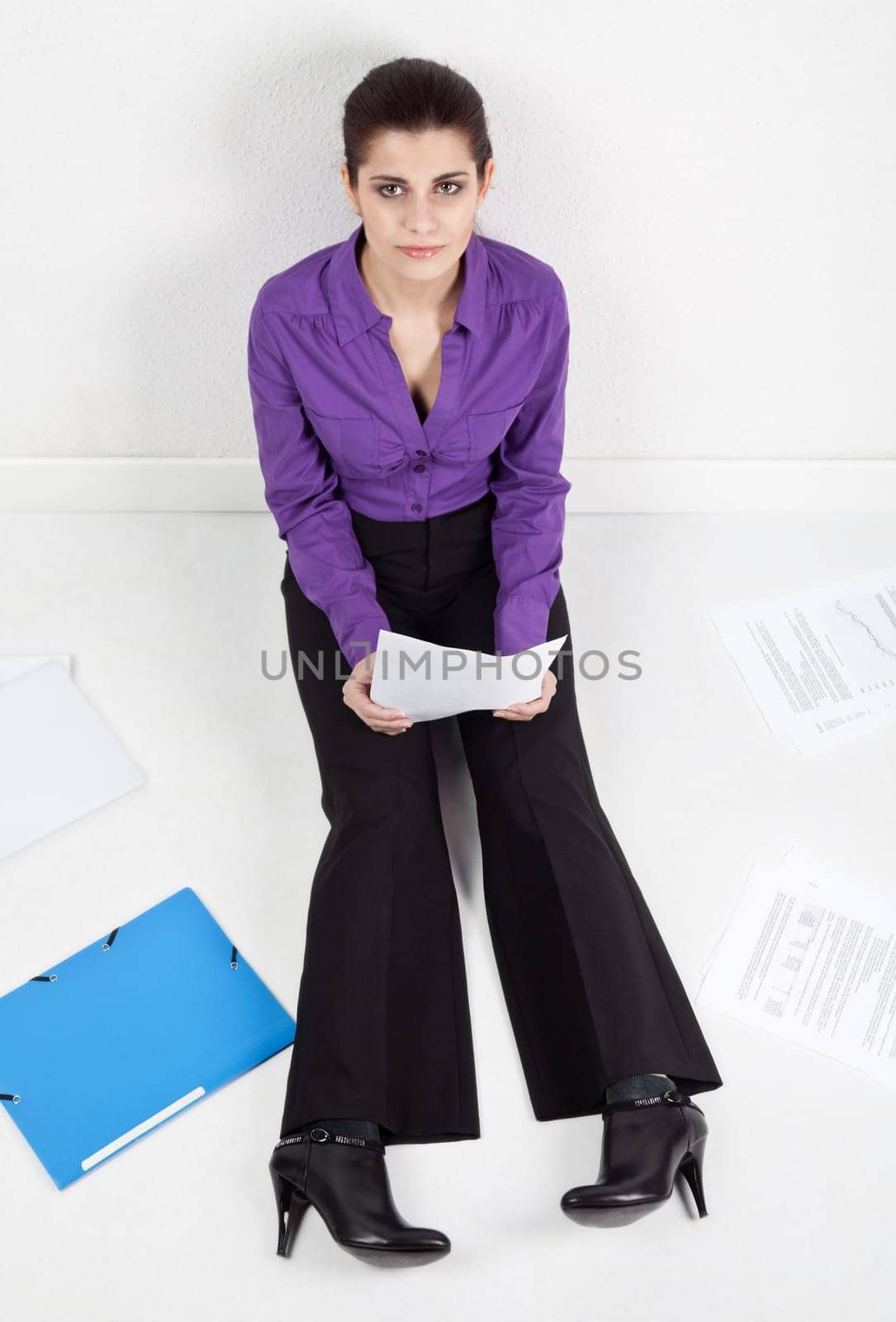 Young pretty secretary sitting on the floor with documents and folders scattered around