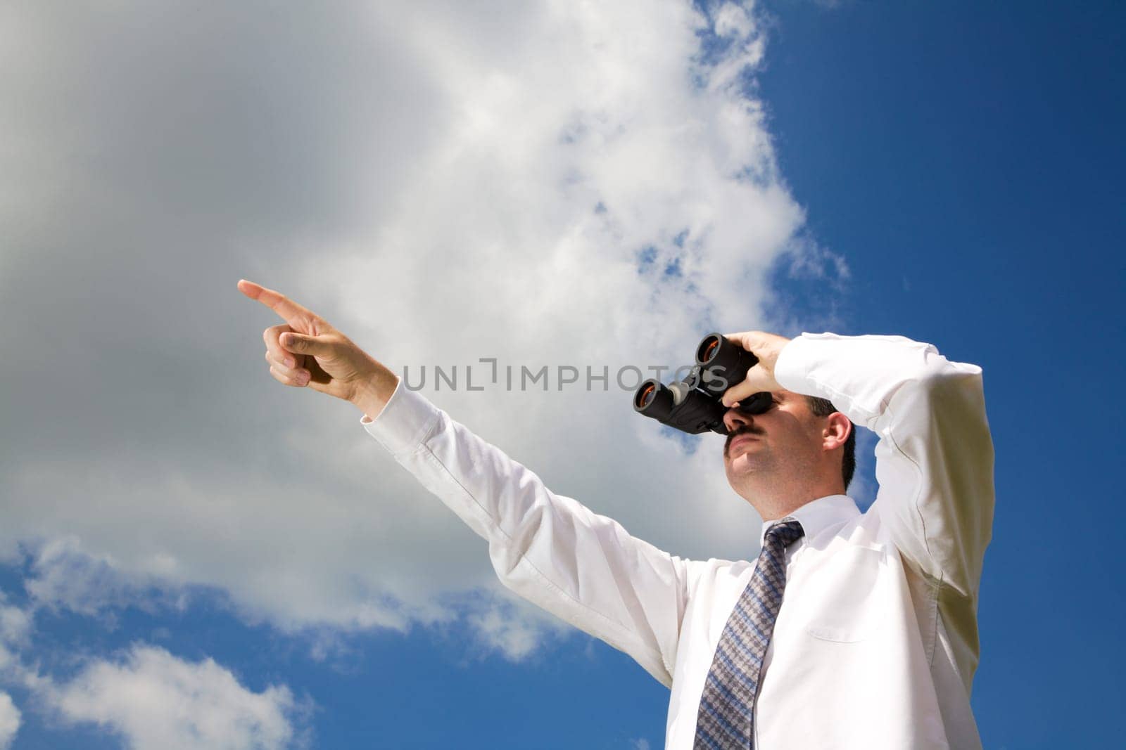 Businessman is looking ahead through binoculars with sky in the background
