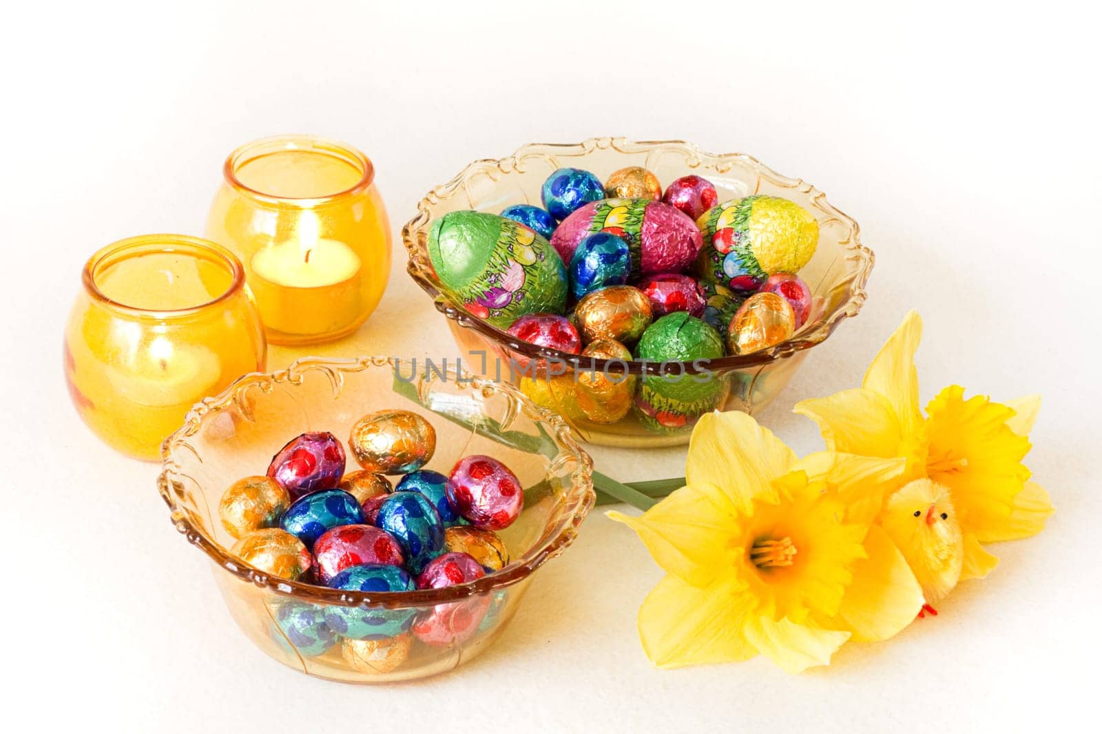 Easter decoration - yellow glass bowls with chocolate eggs, candles and daffodils