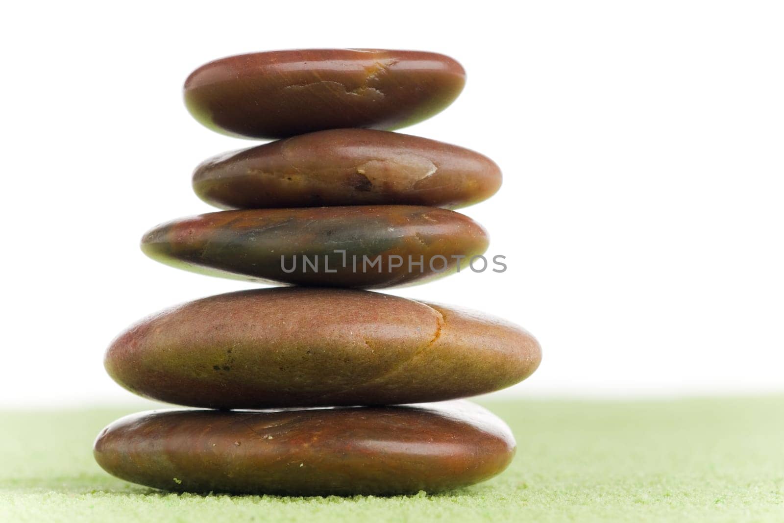 Brown flat stones in balance on green sand