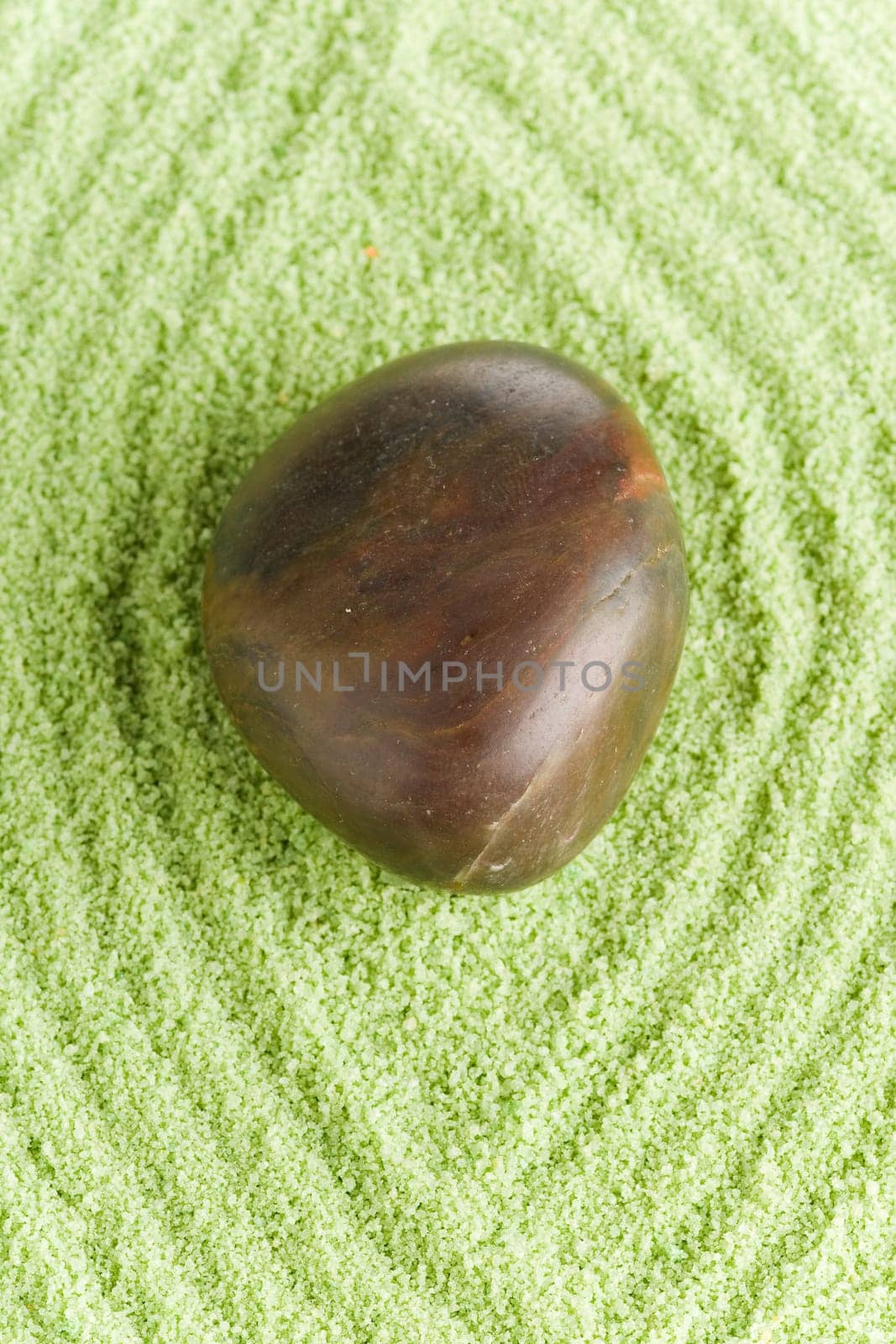 Brown round stone with lines on green sand