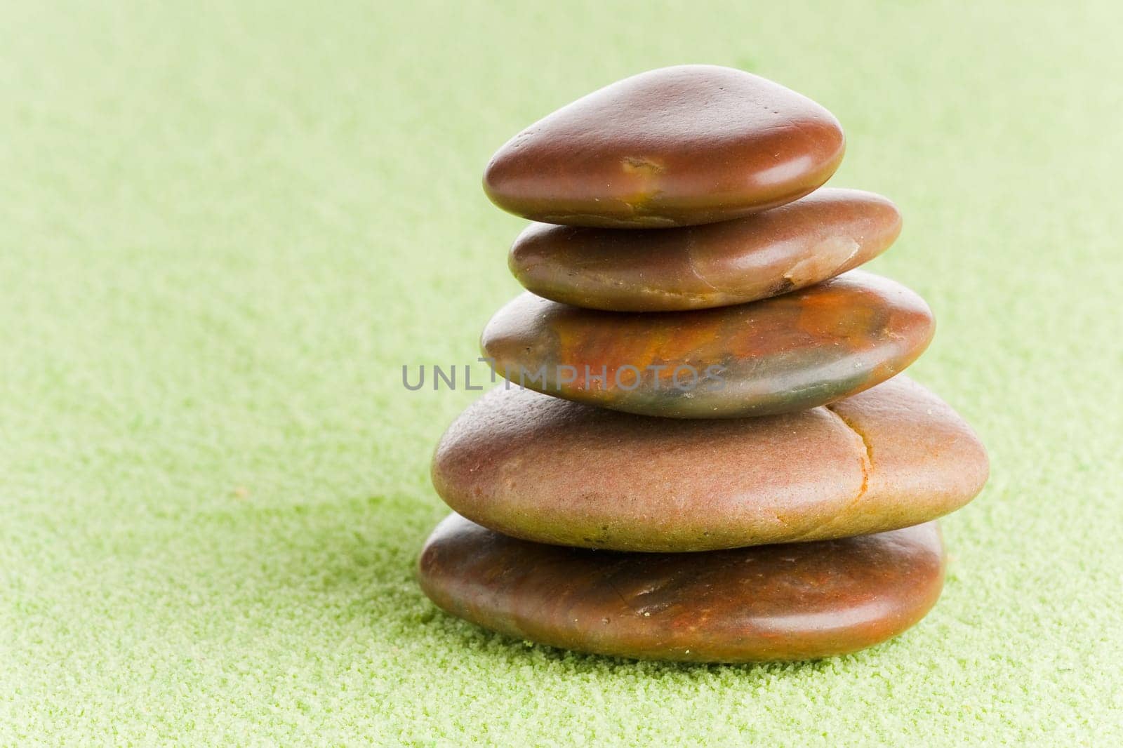 Brown flat stones in balance on green sand