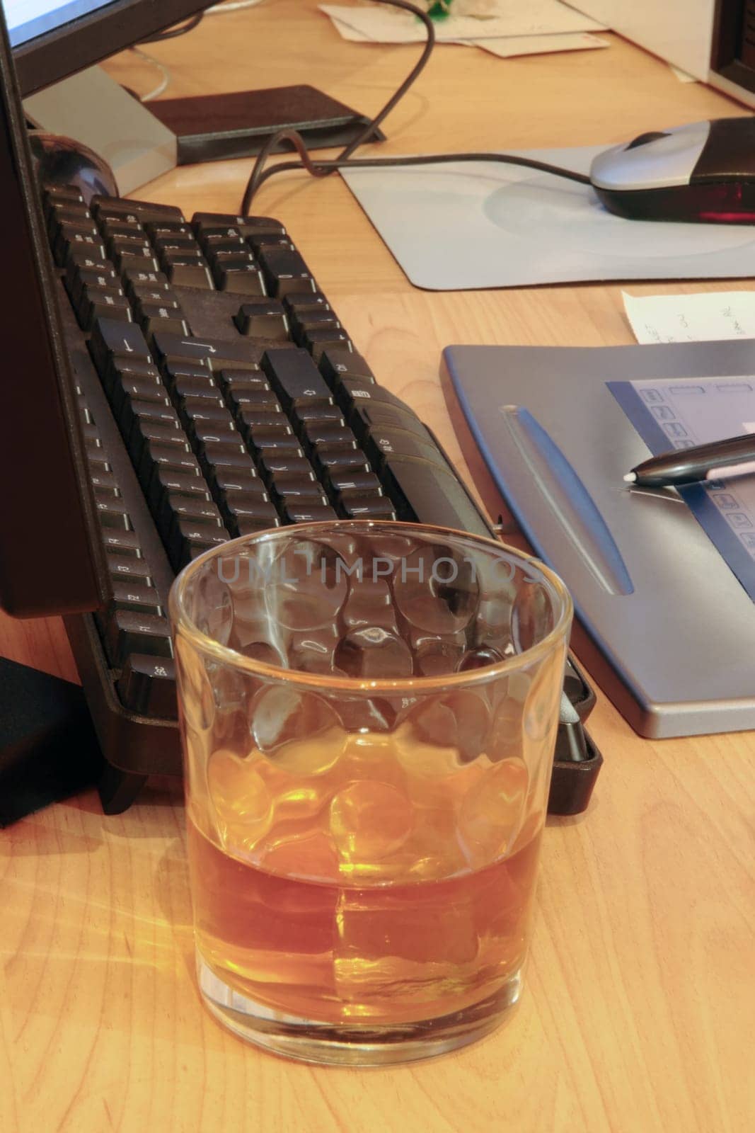 whiskey glass on office desk depicting drinking at work