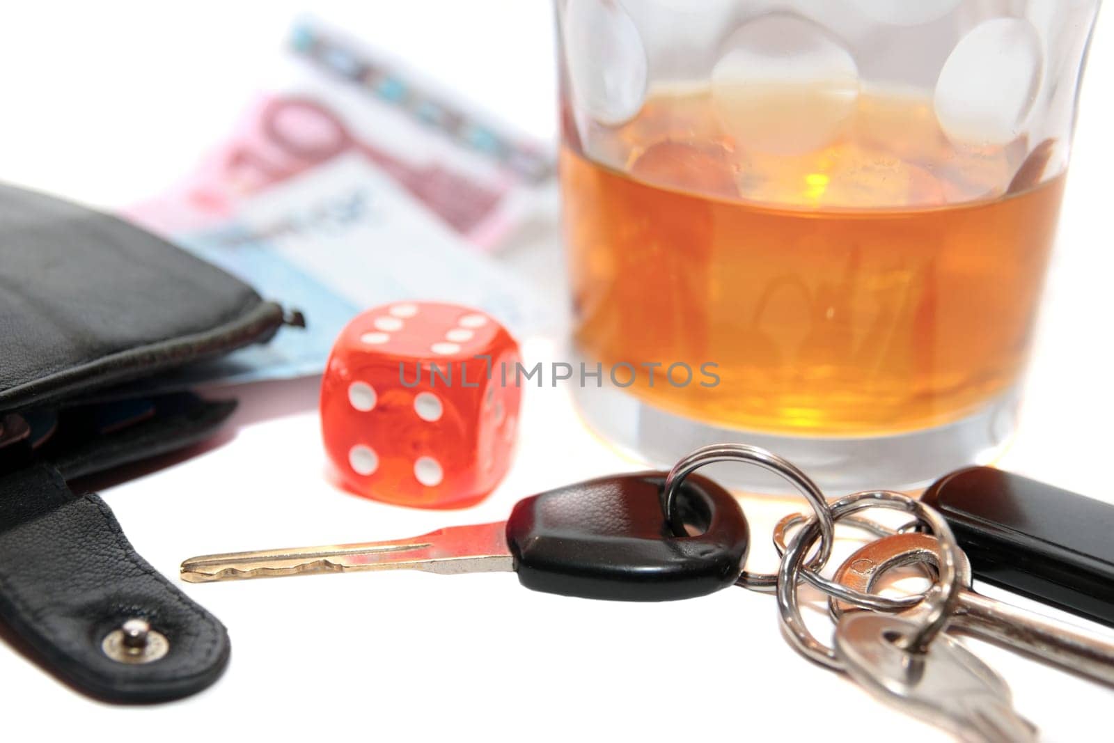 dice and whiskey glass with car keys and cash on white background depicting gambling with drunk driving and addictions can kill