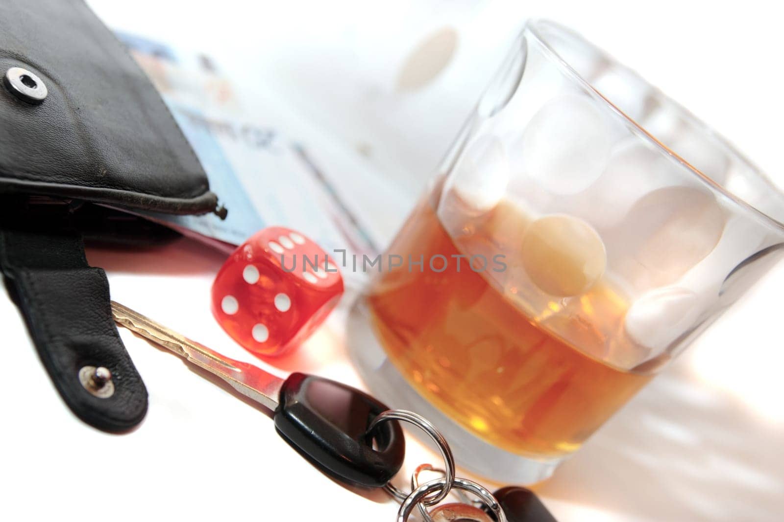 dice and whiskey glass with car keys and cash on white background depicting gambling with drunk driving and addictions can kill