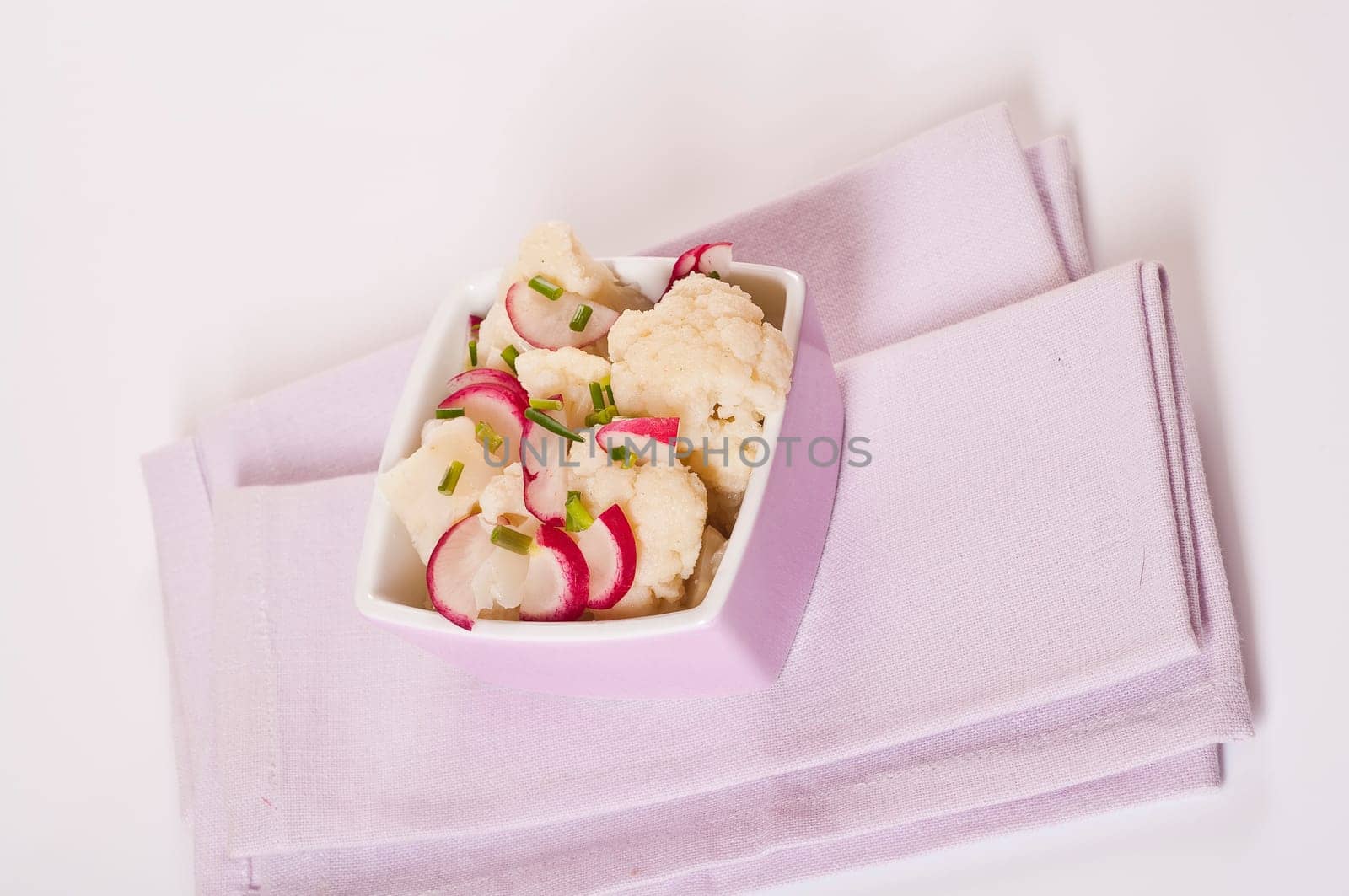 Cauliflower salad with radishes in pink bowl
