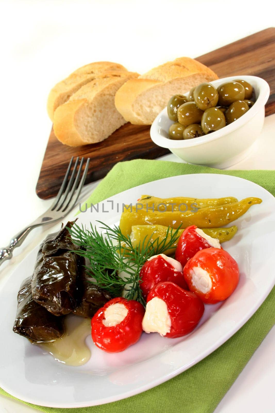 Stuffed pepperoni,vine leaves and green olives against a white background