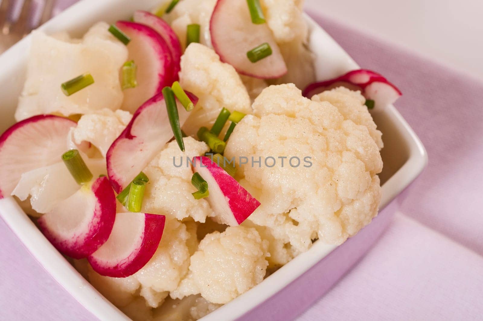 Cauliflower salad with radishes in pink bowl