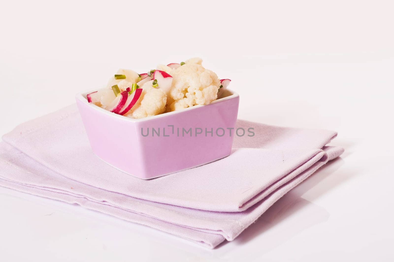 Cauliflower salad with radishes in pink bowl