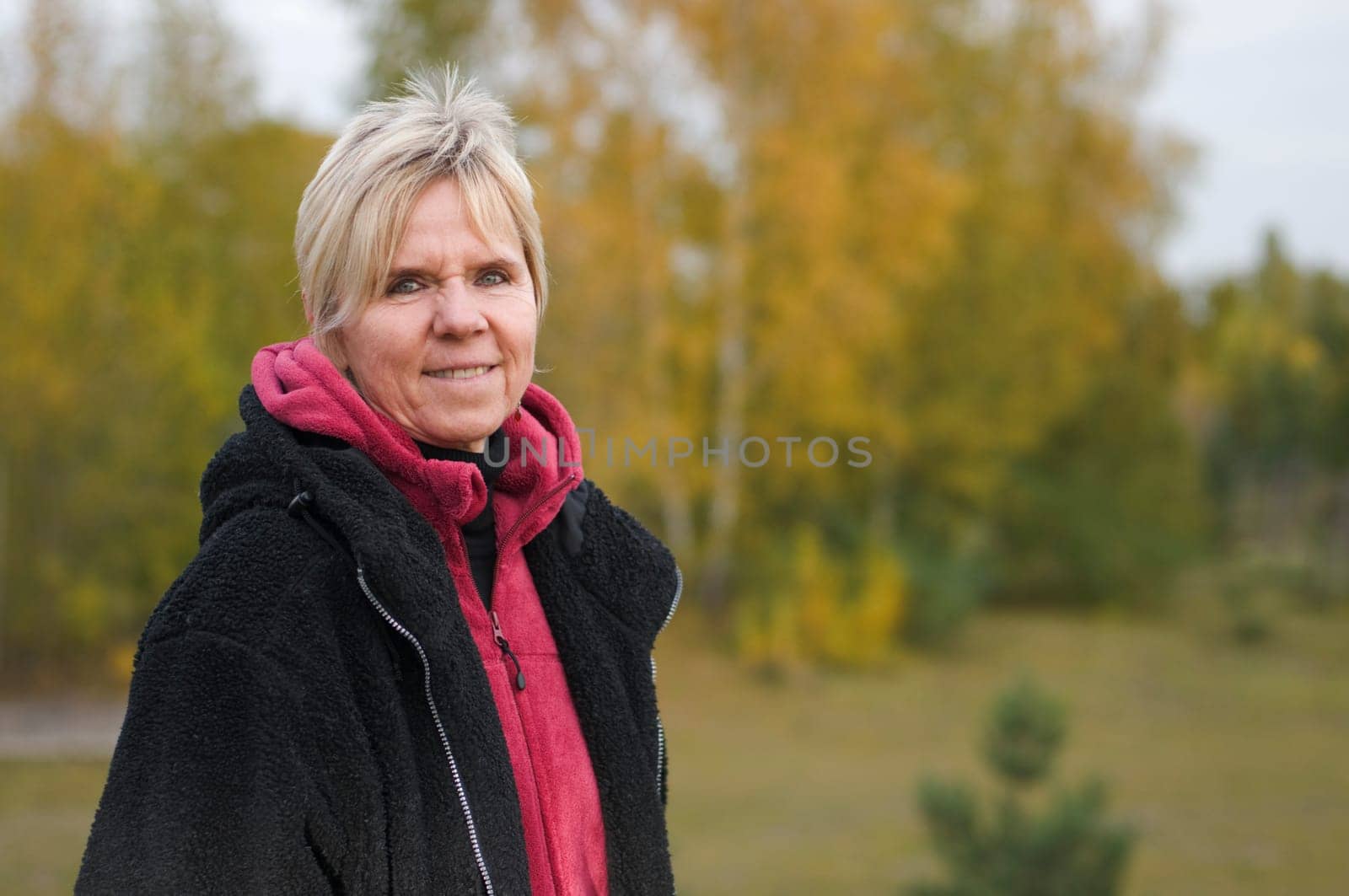 Outdoor portrait of an elderly woman in a black jacket against a natural background