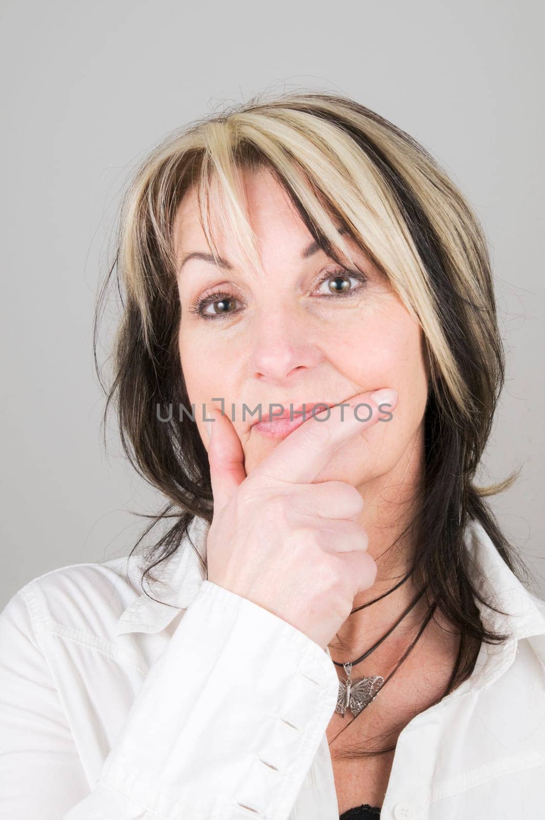 Head and shoulders shot of mature blonde woman with dark streaks in brooding/pensive pose