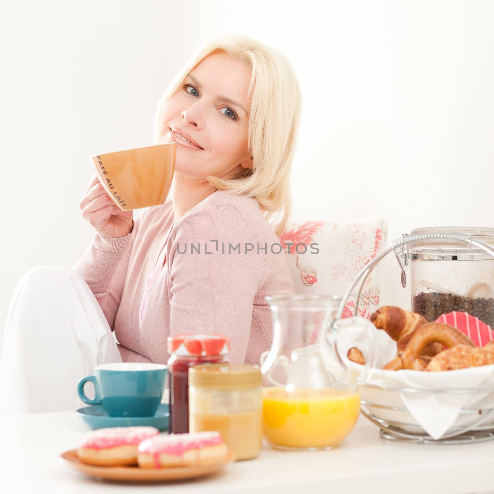 Young and blonde woman sitting at a breakfast table