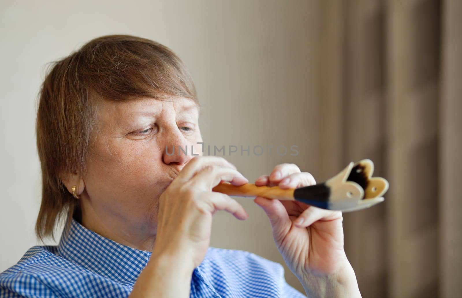 Elderly woman playing a wind instrument at home