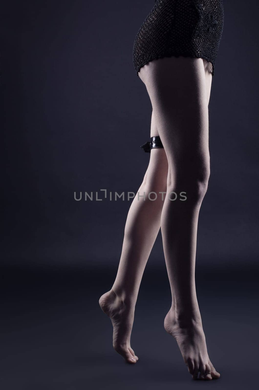 Woman legs in dark with leather belt - gothic style