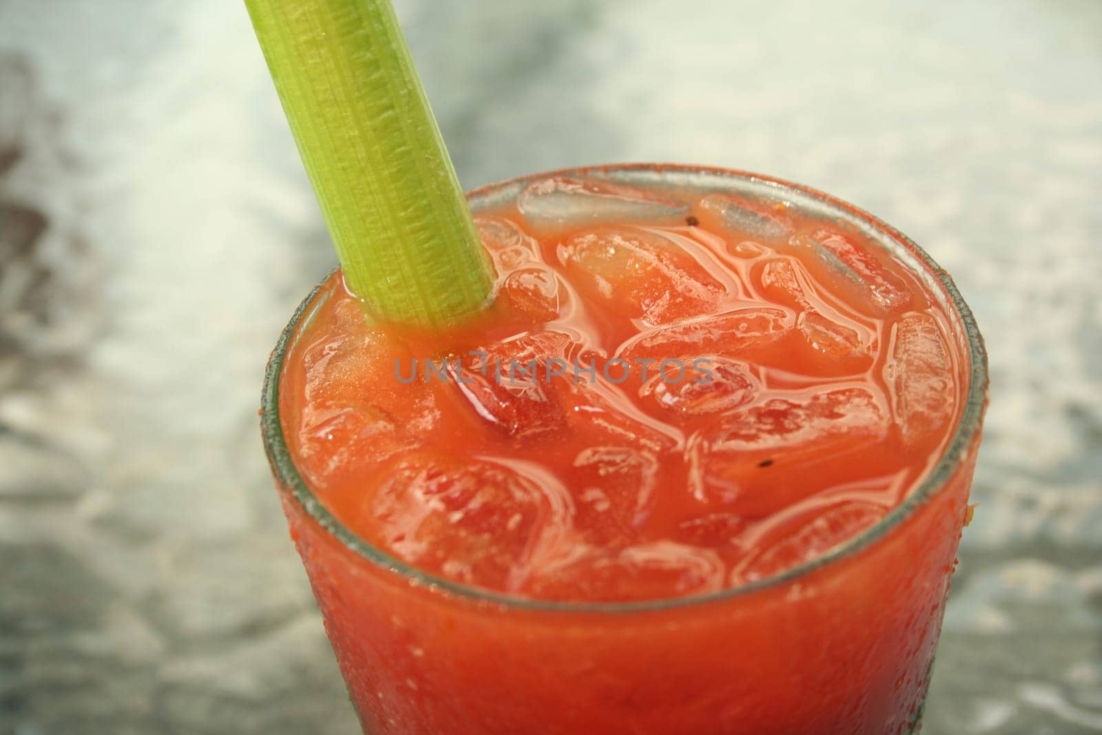 a Bloody Mary Coctail with celery on a glass table