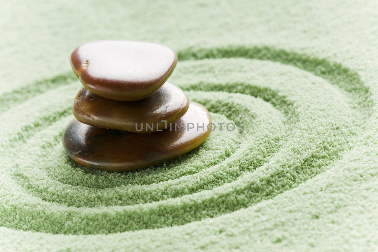 Brown stones in balance in a circle on green sand