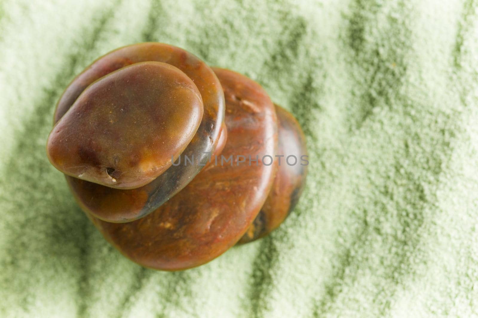 Brown stones in balance on green sand