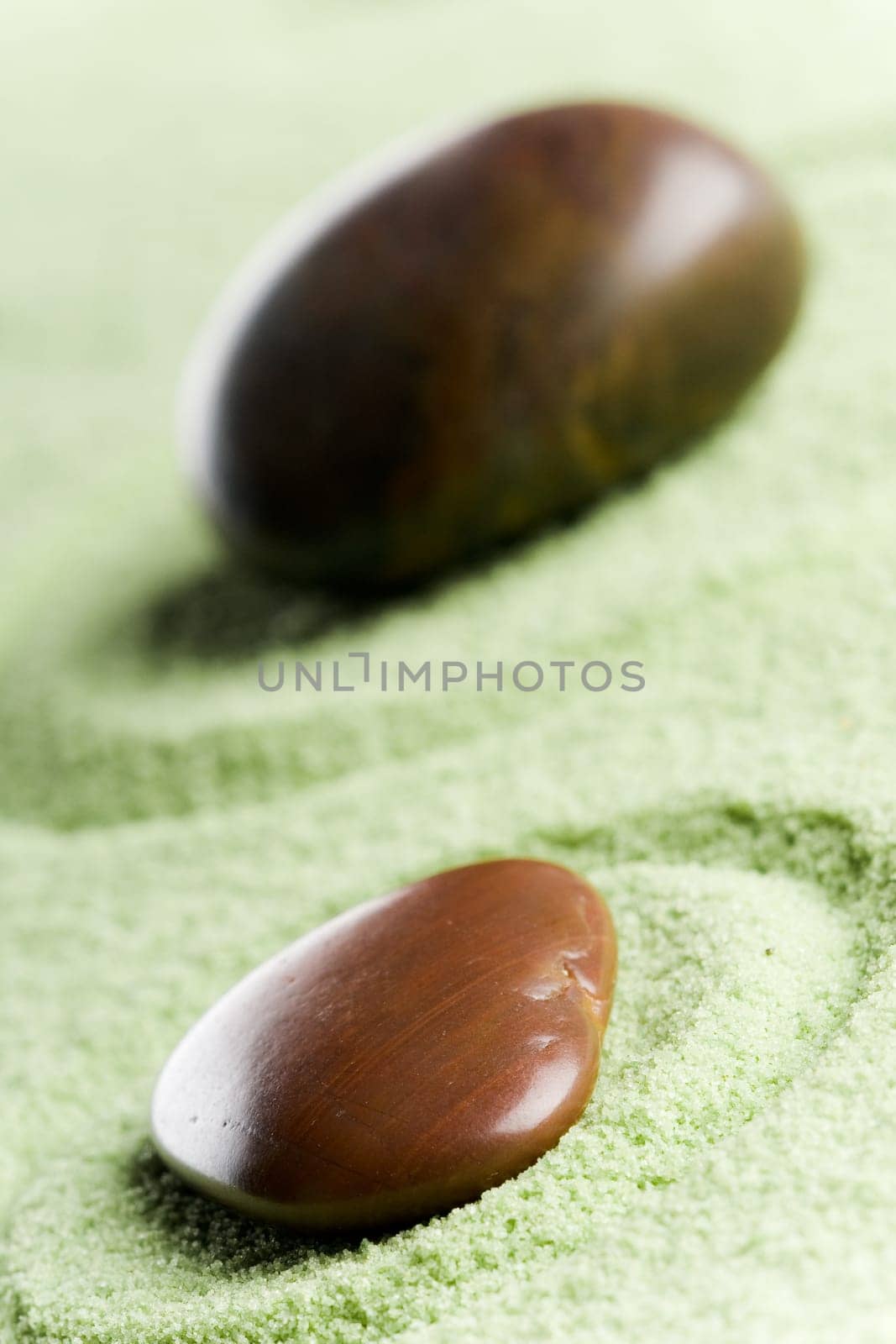 Brown stones in balance in a circle on green sand