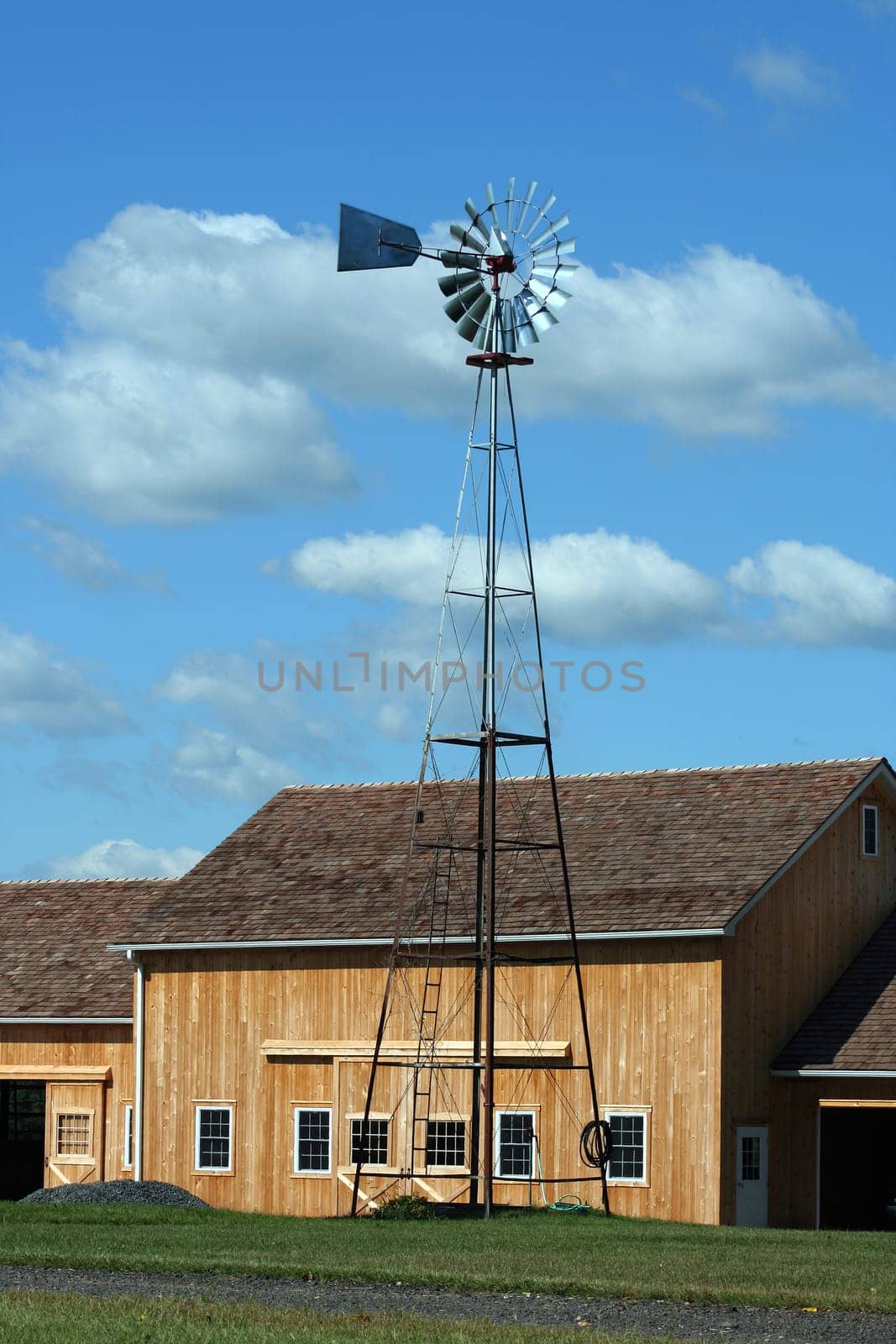 A Windmill with new barn against a cloudy blue sky