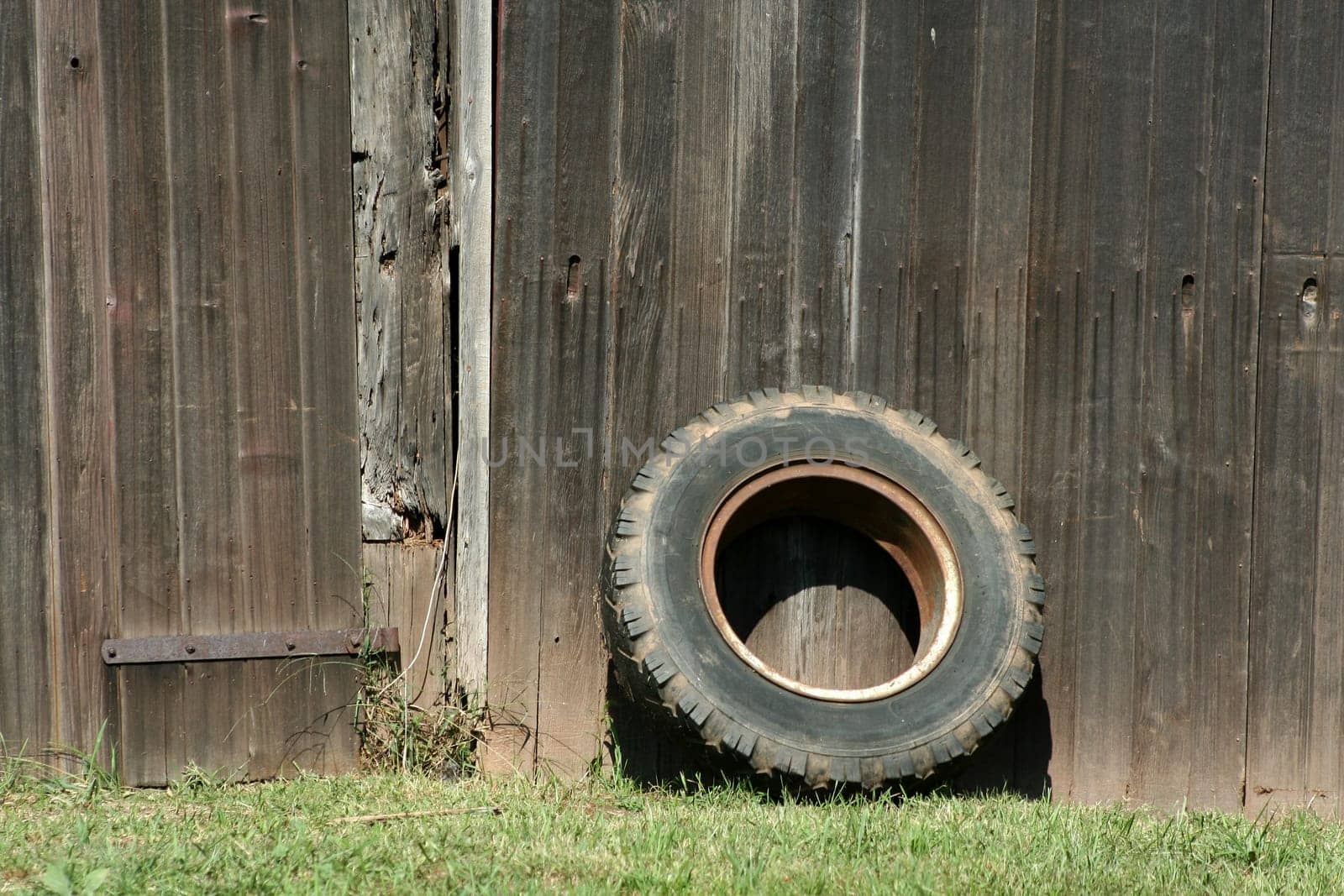 A Tire leaning on a old barn