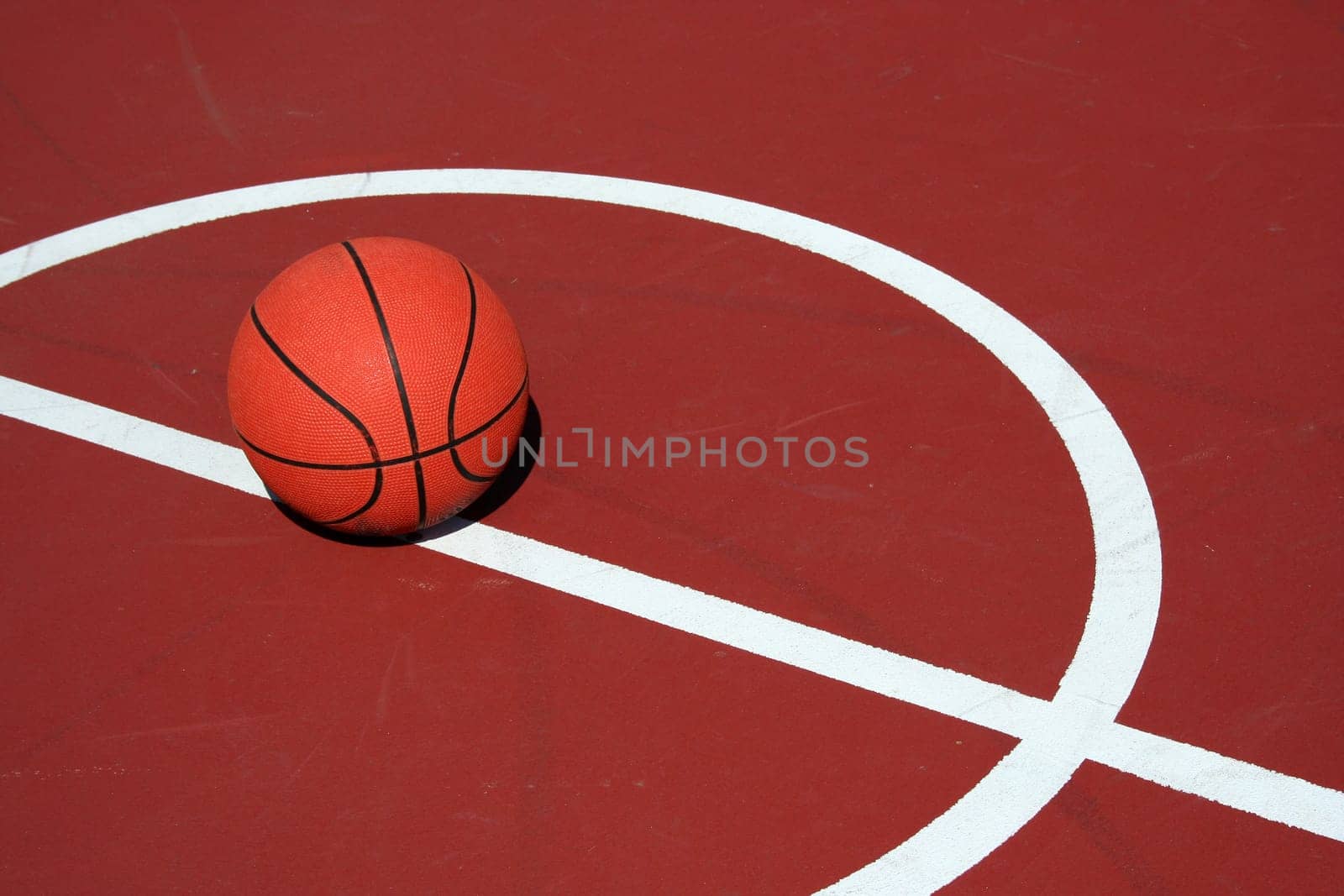 A Basketball at center court on a red court