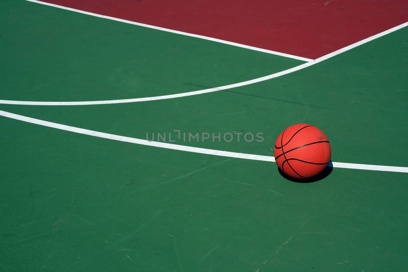A Basketball at  three point line on red and green court