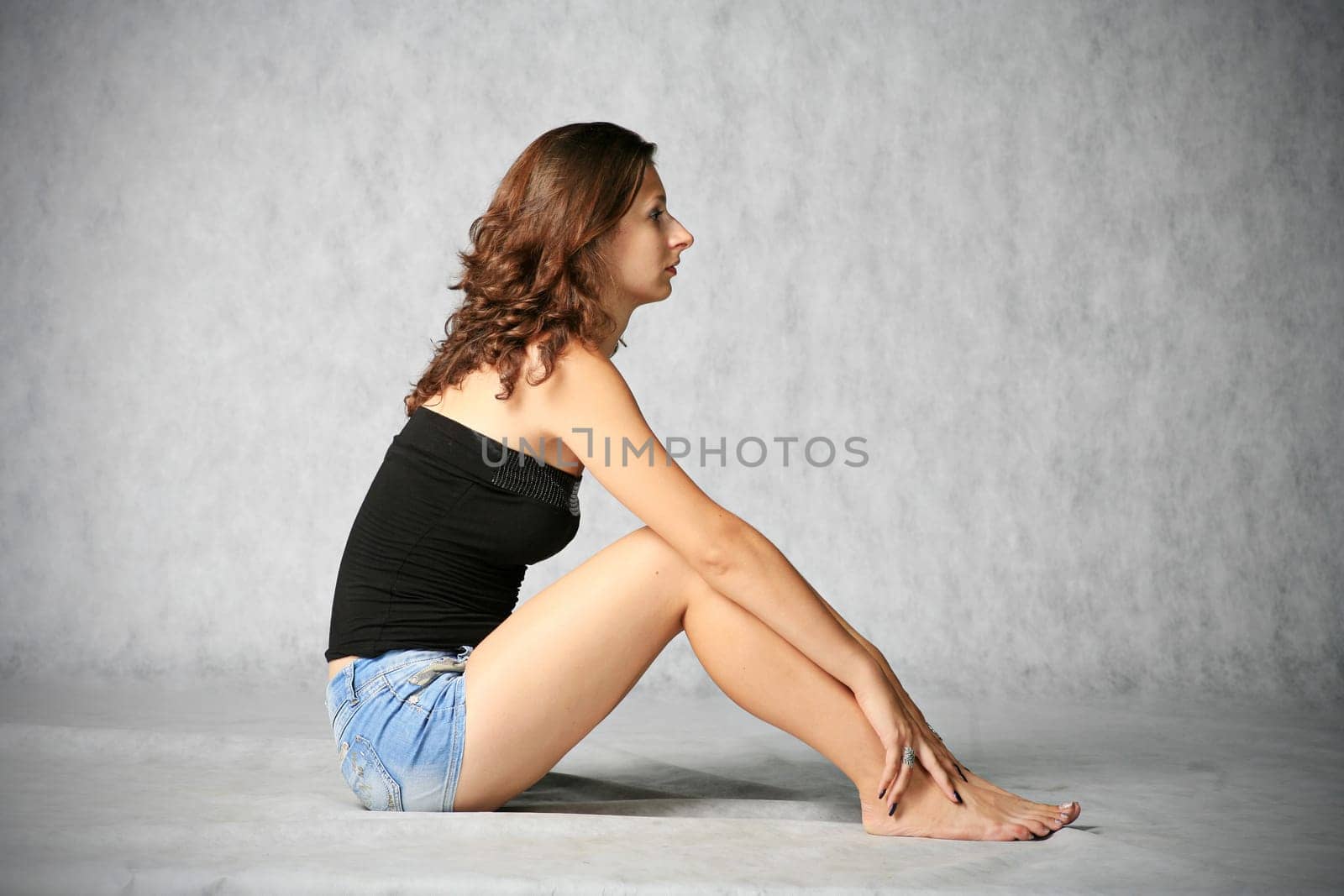 portrait of sexy brunette sitting on the grey background
