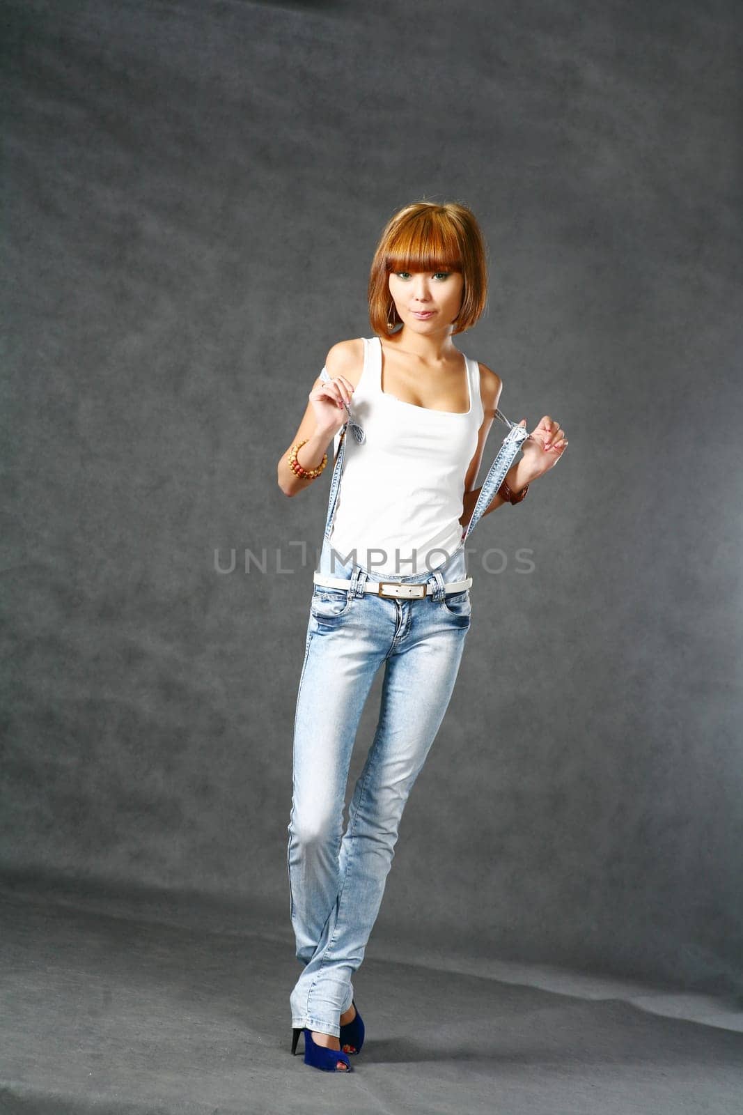 Beautiful Japanese girl in jeans over dark grey background