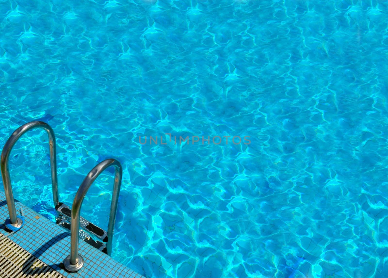 pattern of water of swimming pool with light in it and pool&#039 s stairway