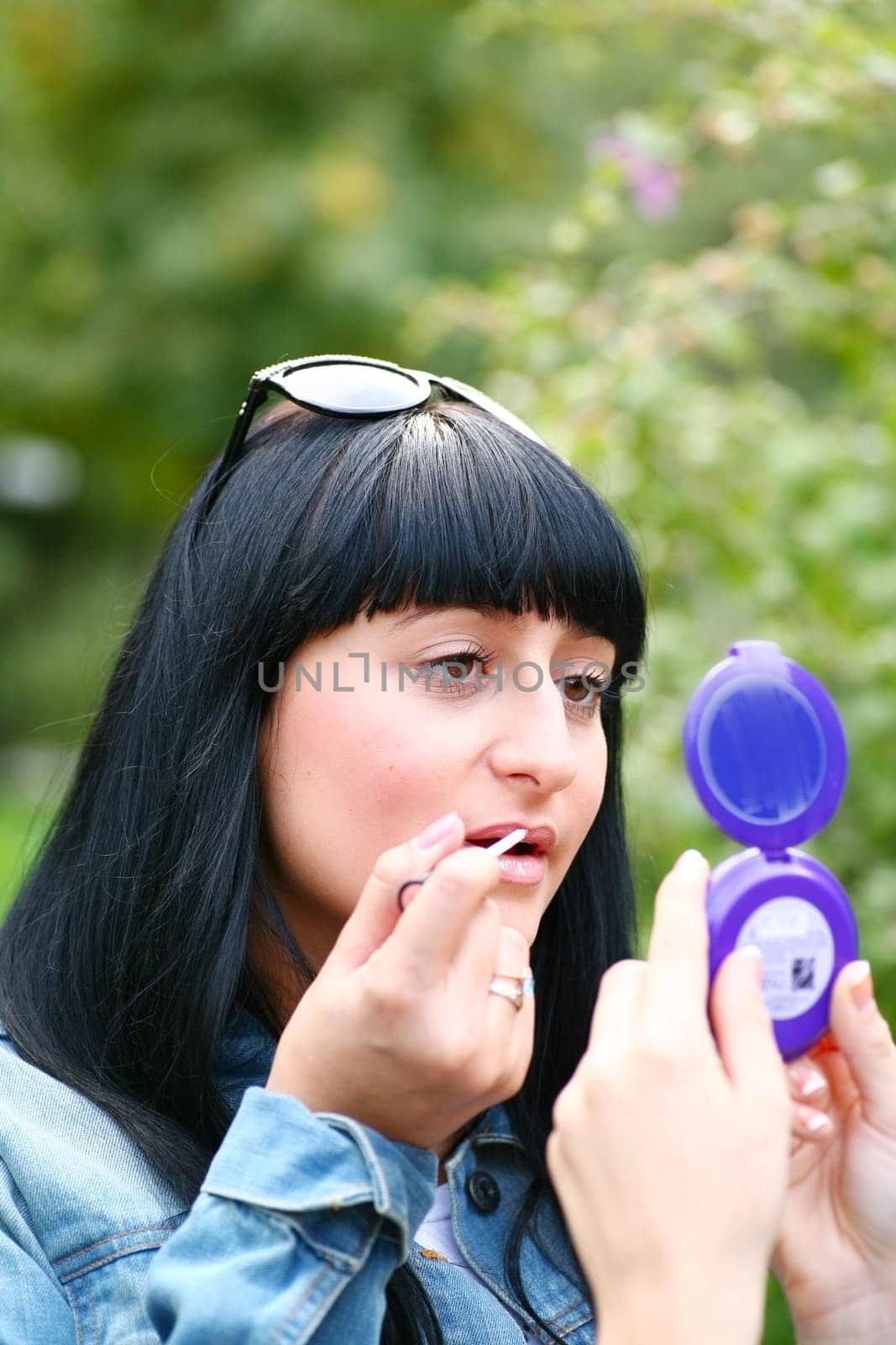 A young woman applying makeup on her lips