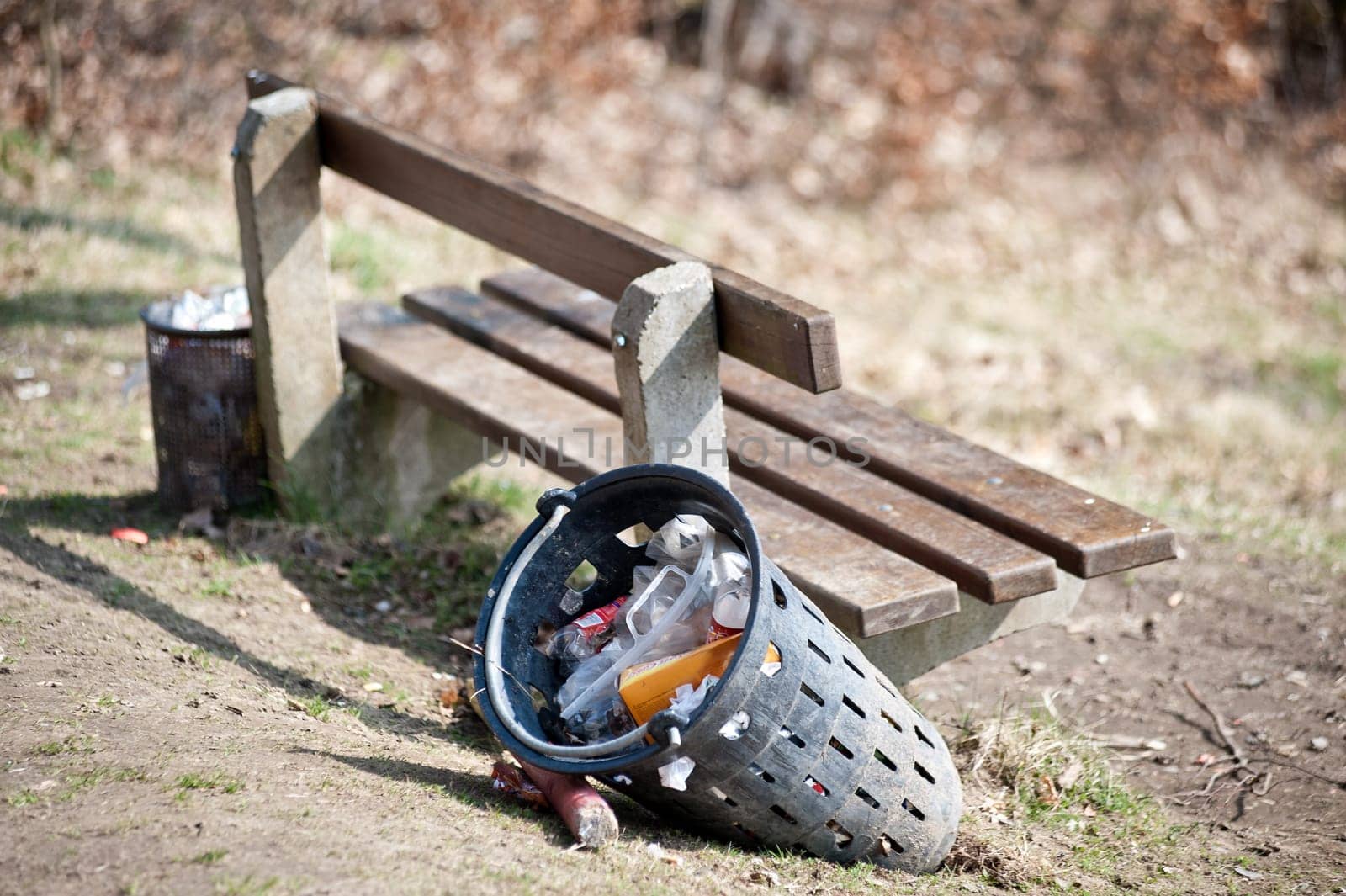 Seating bench with full garbage can in the nature