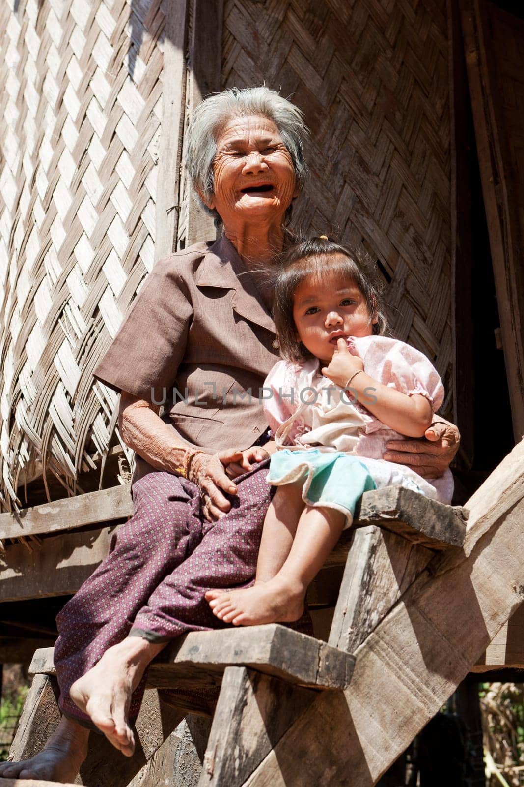 Asian grandmother with grandchild,portrait in front of Laotian house
