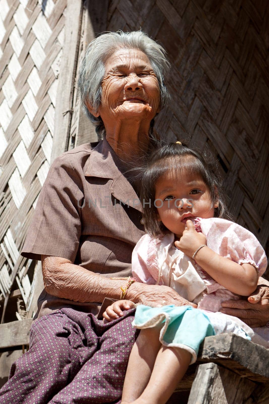 Asian grandmother with grandchild,portrait in front of Laotian house