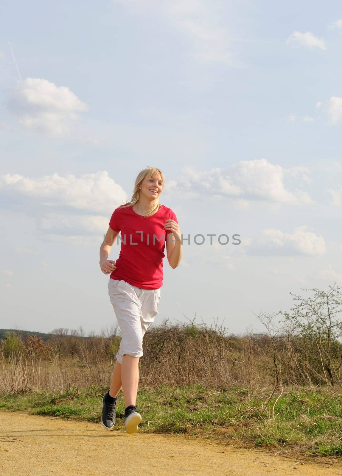 Young woman jogging on a dirt road