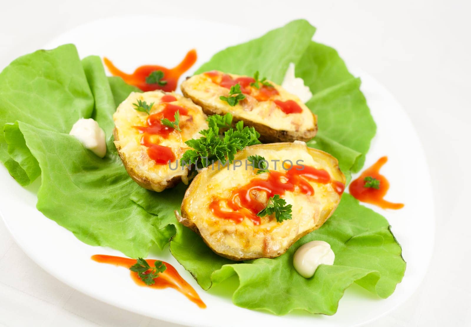 Baked potatoes filled with ham, eggs and cheese, decorated with parsley, ketchup, mayonnaise and lettuce